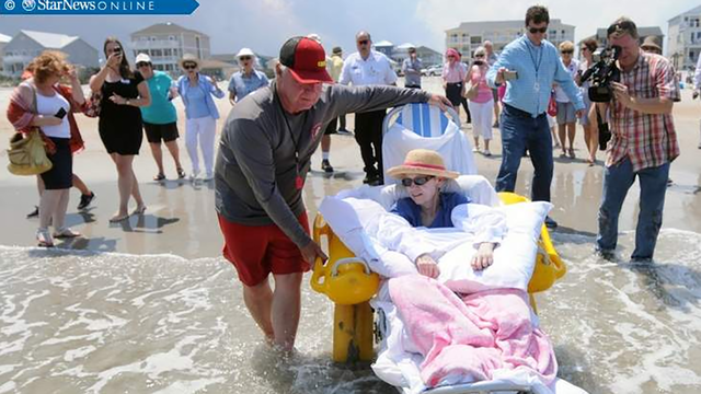 Carolina Beach Ocean Rescue lifeguard Dan Anderson wheels Ellie Duckett down to the water on Friday at Carolina Beach. Her last wish was to see the beach one more time before she died.